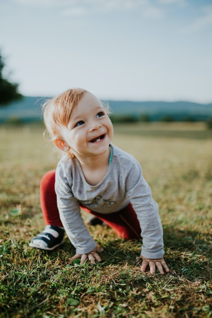 selective focus photo of baby crawling on grass