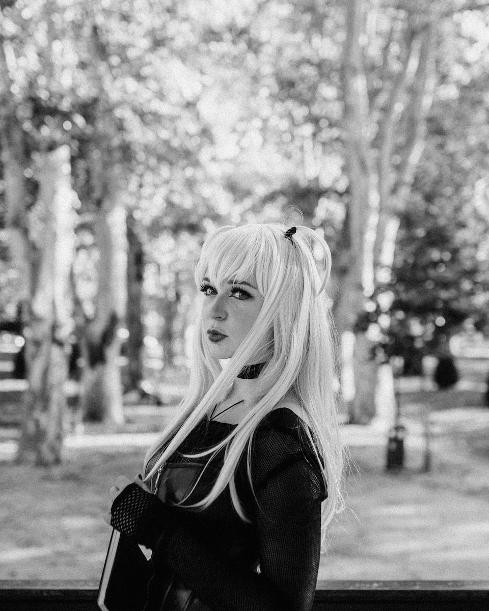 a woman with long blonde hair standing in a park