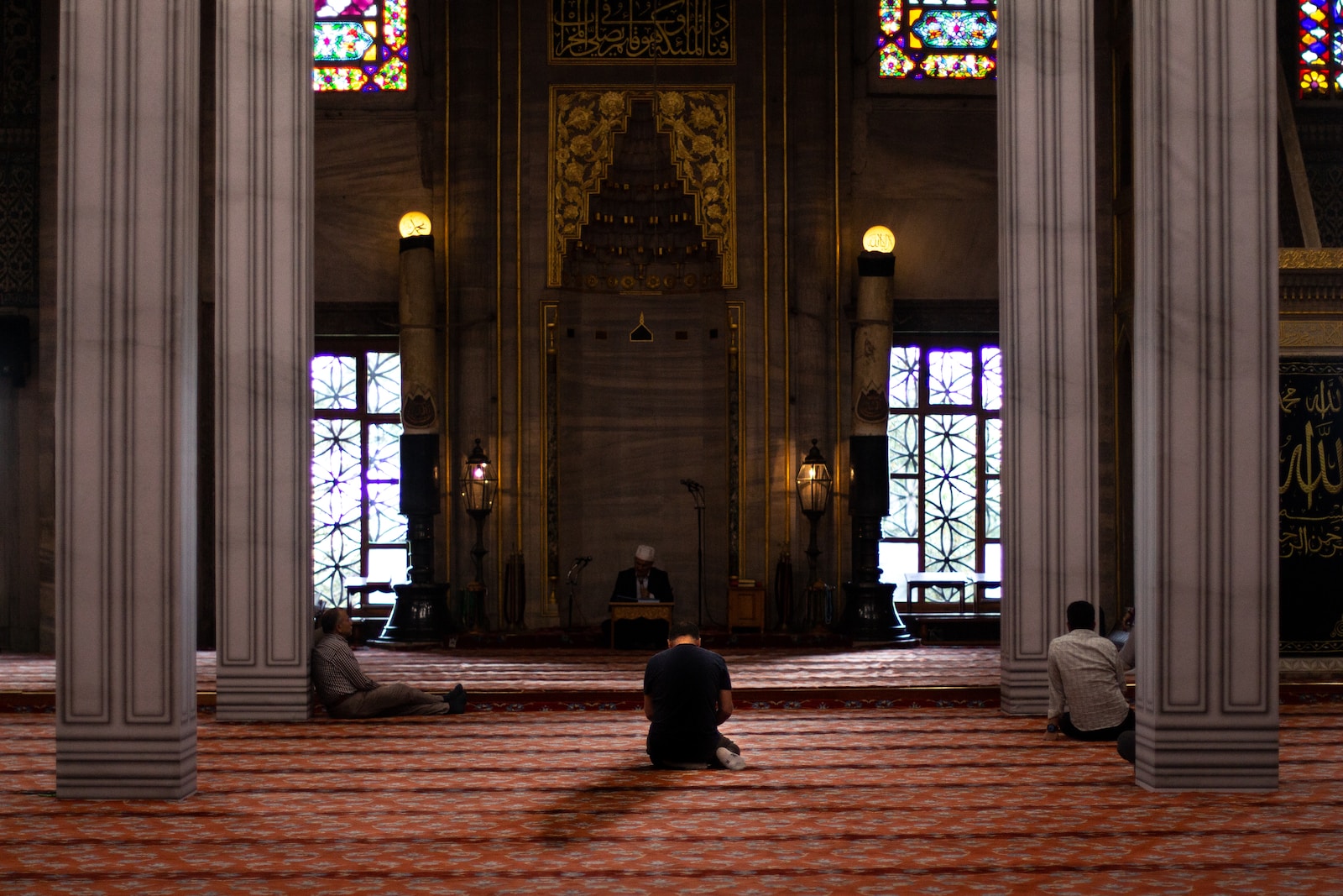 three men sitting inside mosque