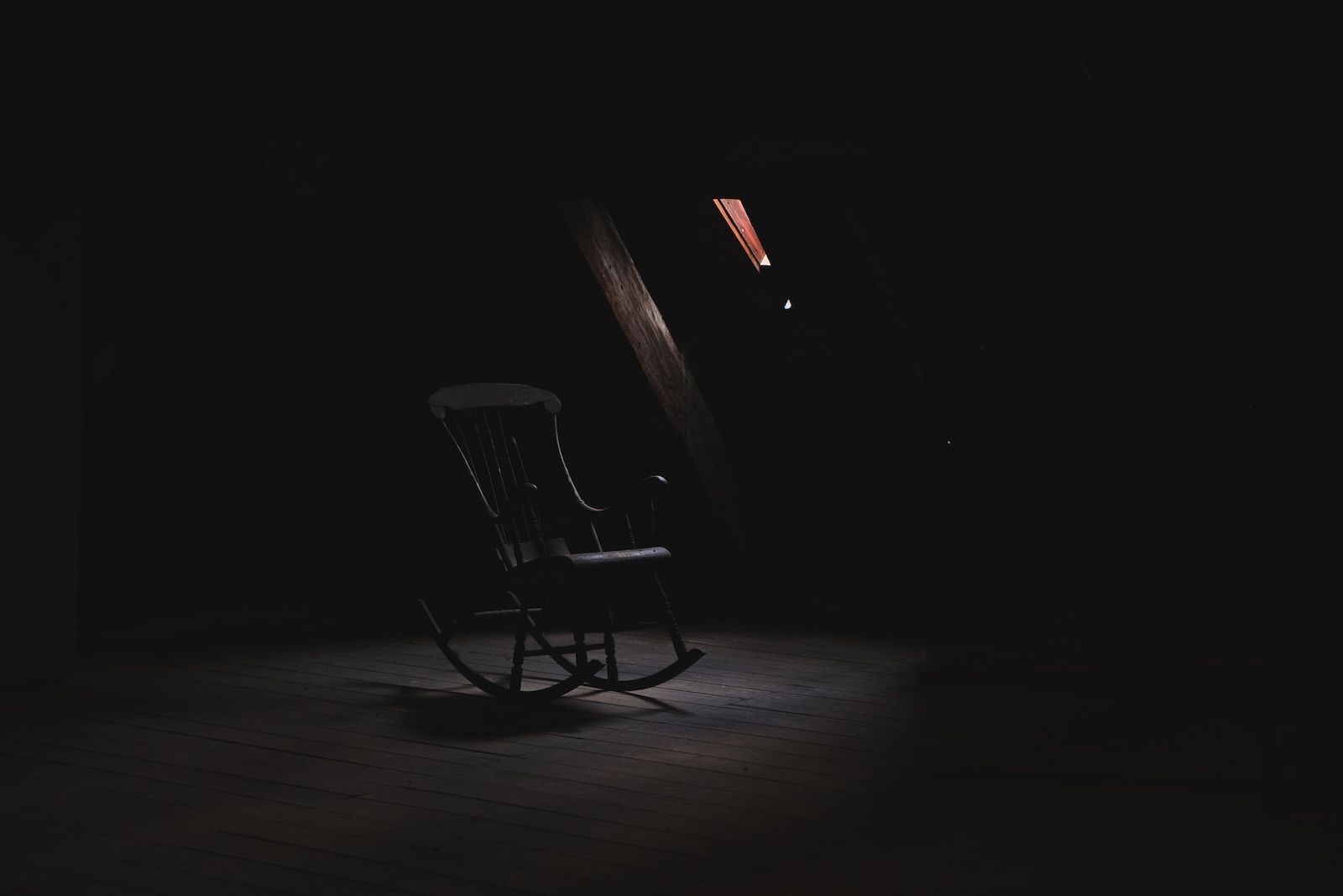 brown wooden rocking chair inside dark room