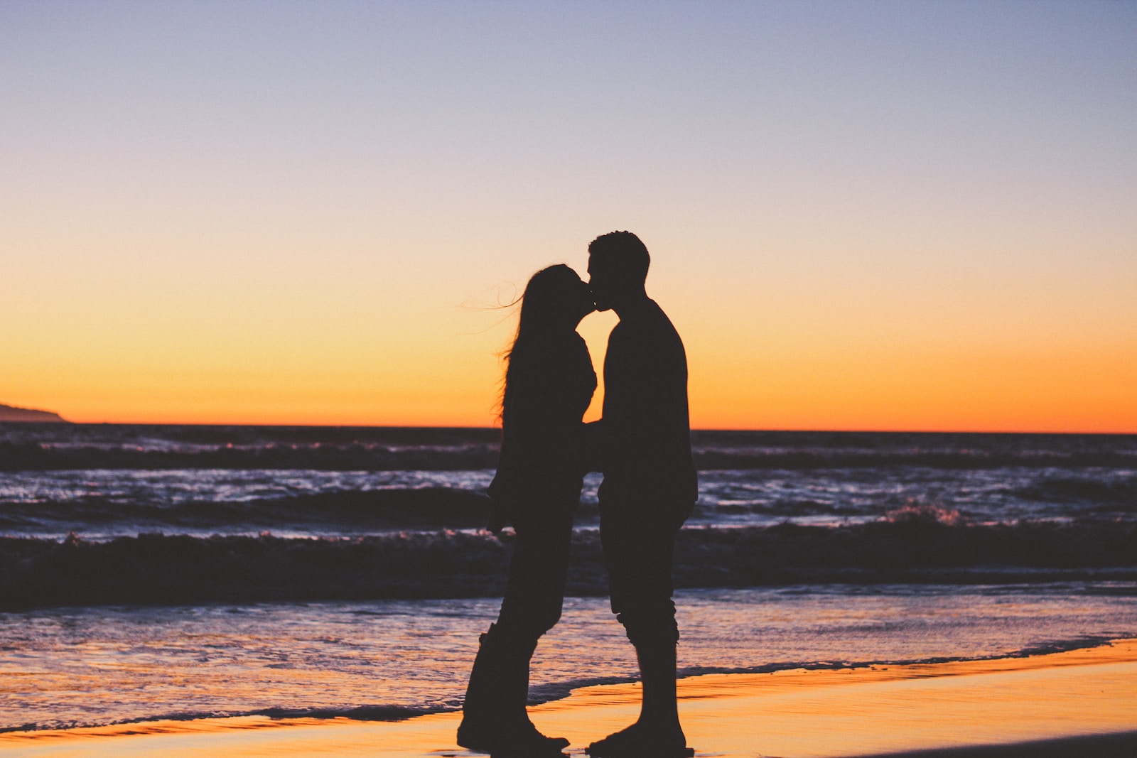 silhouette of couple sitting on seashore
