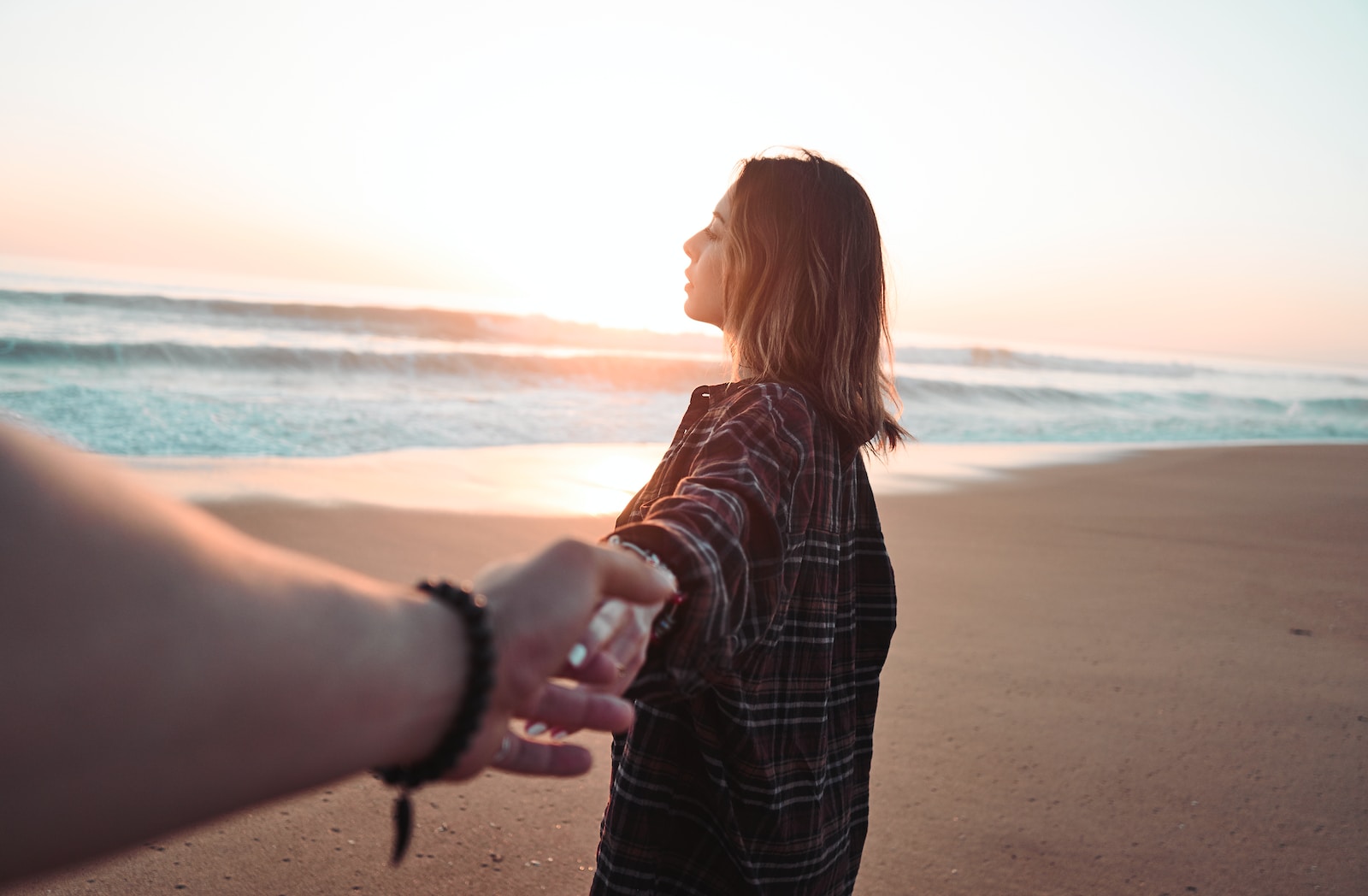 woman holding hands with person facing ocean