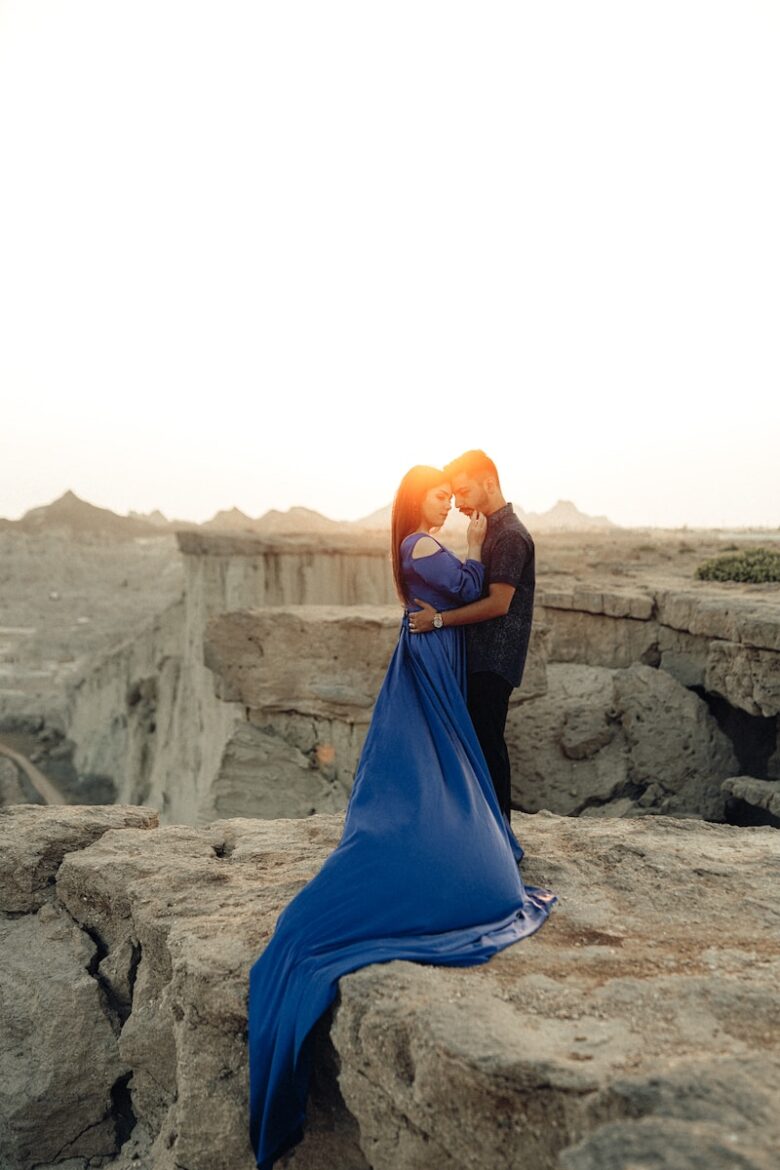 a man and a woman are kissing on a rock
