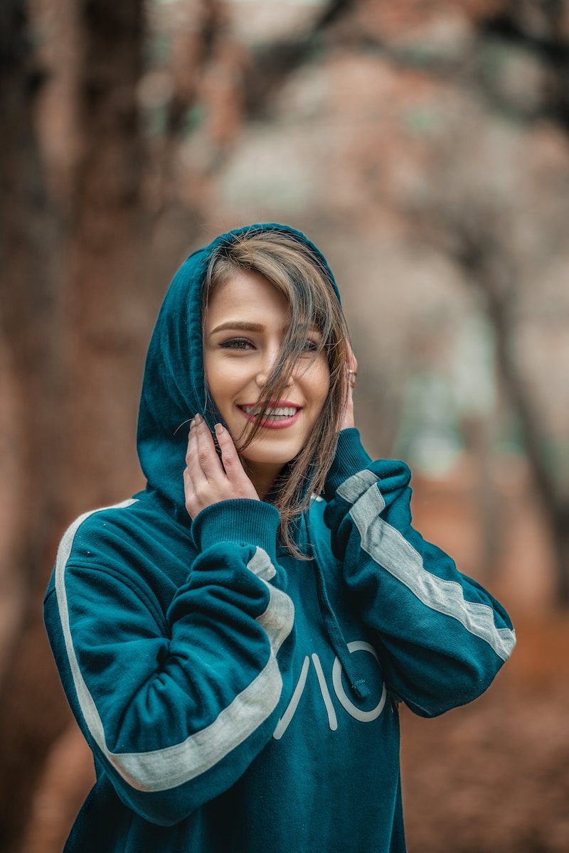 smiling woman wearing blue hoodie in selective focus photography