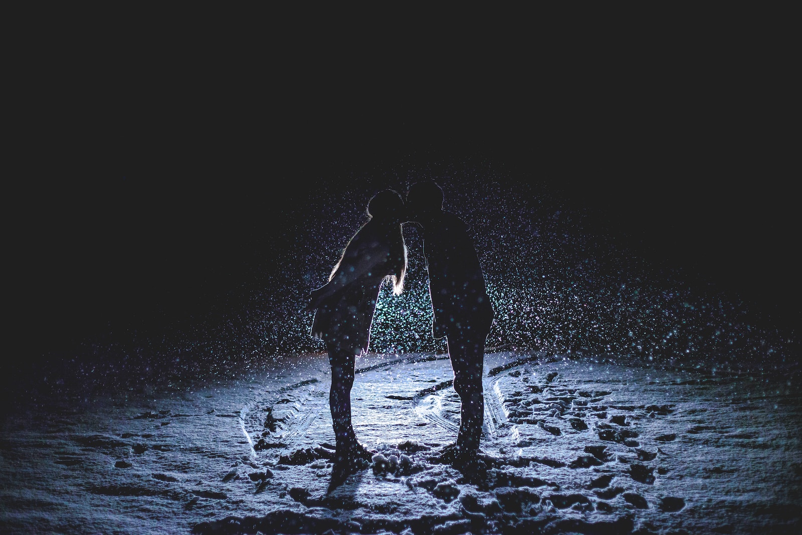 man and woman kissing in the middle of the rain