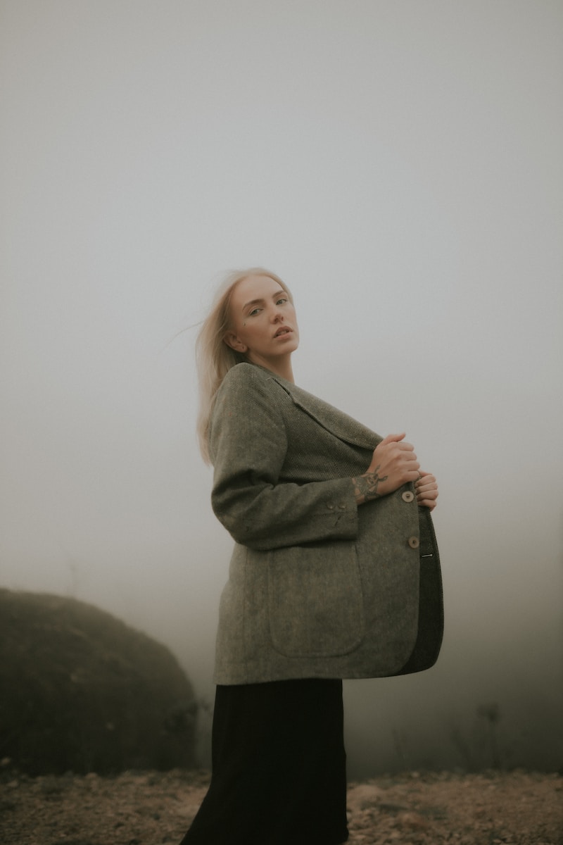 a woman standing in the fog with her arms crossed