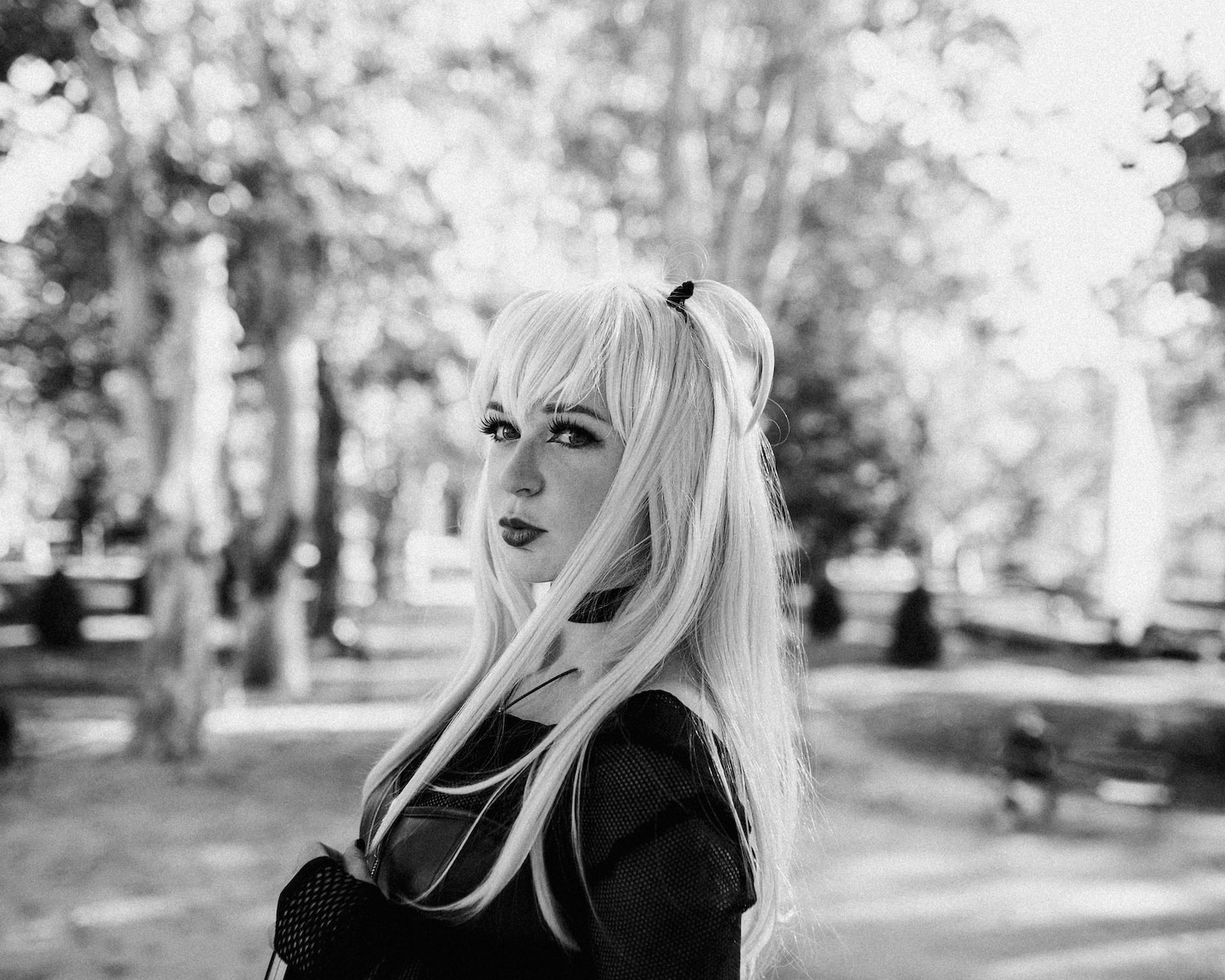 a woman with long white hair standing in a park