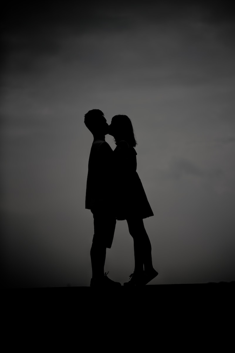 silhouette photo of man and woman kissing