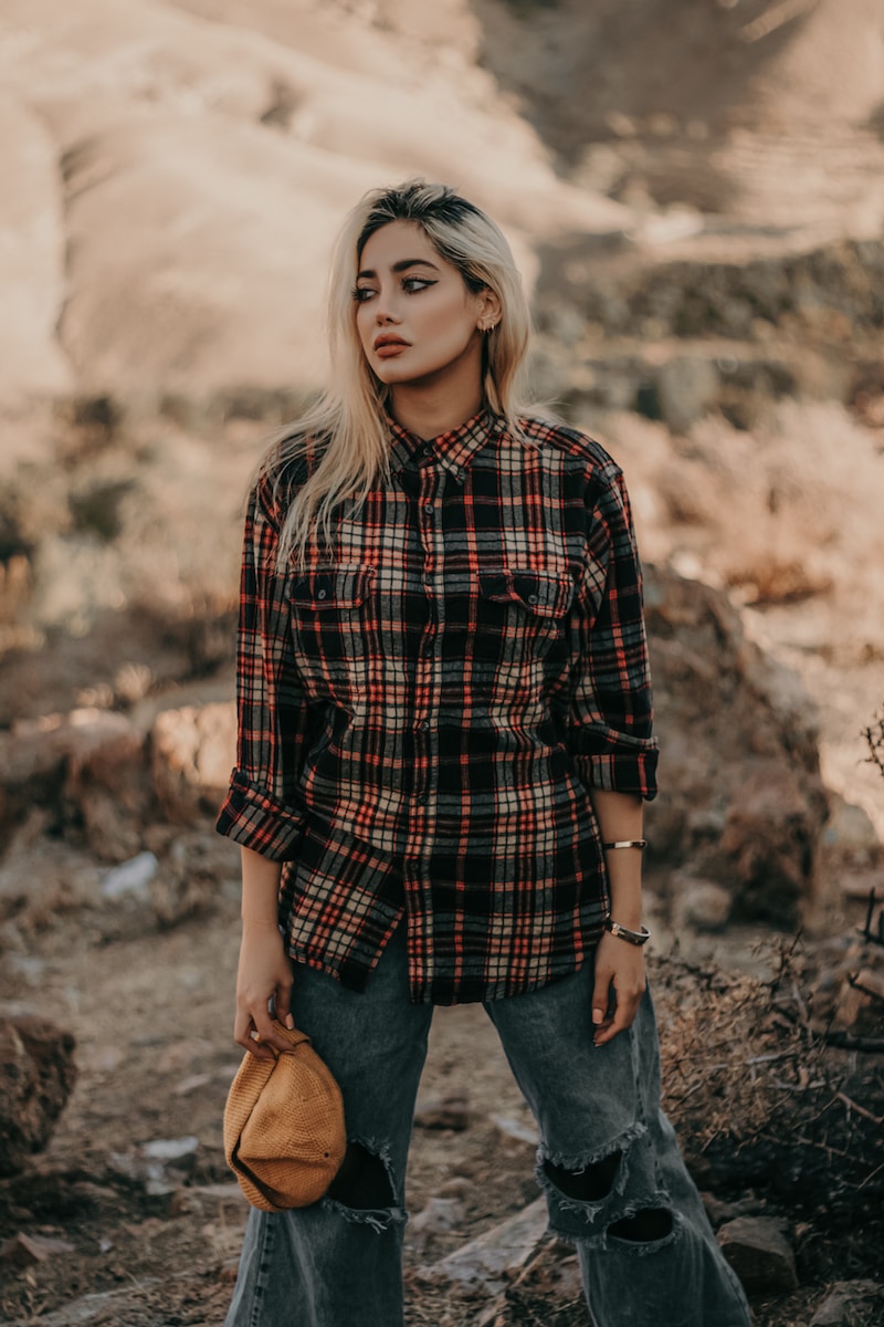 woman in black red and white plaid dress shirt and blue denim jeans standing on brown